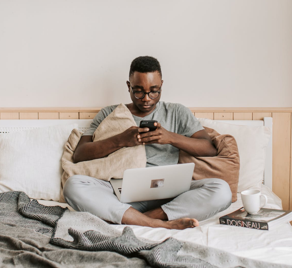 retos del trabajo a distancia, trabajador con portátil y teléfono en la cama sin poder desconectar